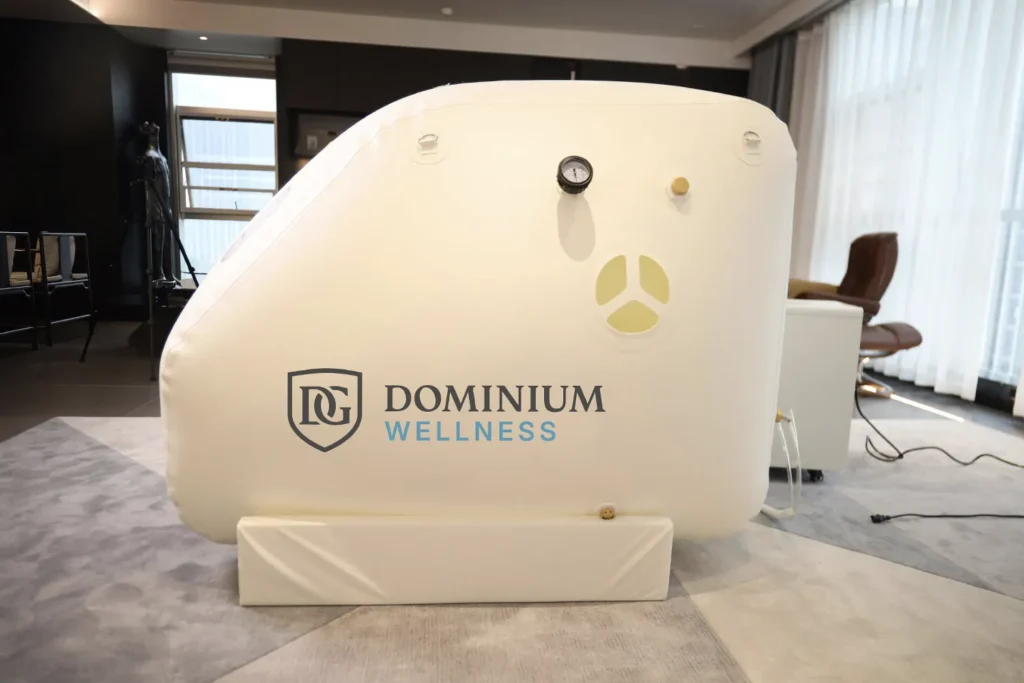 Basınç göstergeli, “Dominium Wellness” logolu beyaz DW160MS model hiperbarik kabin. Modern bir odada; sakin, terapötik bir ambiyans yayıyor.
